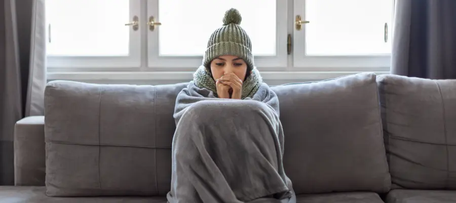 Young woman shivering on the sofa