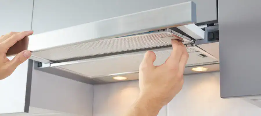 A man replaces a range hood filter