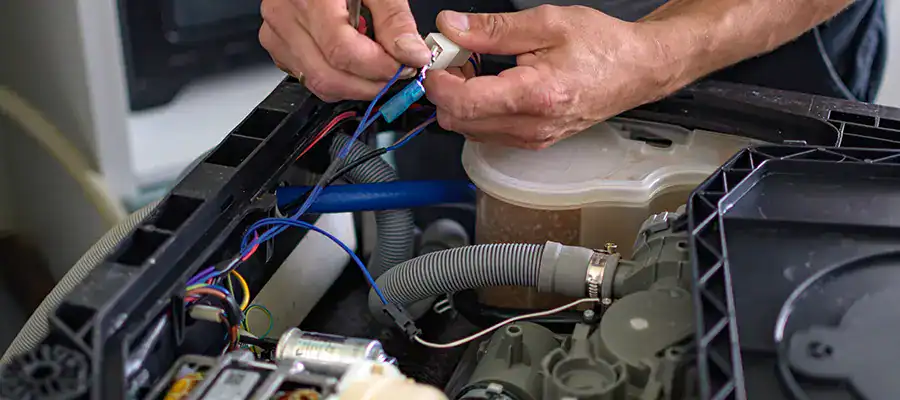 A technician repairs a dishwasher